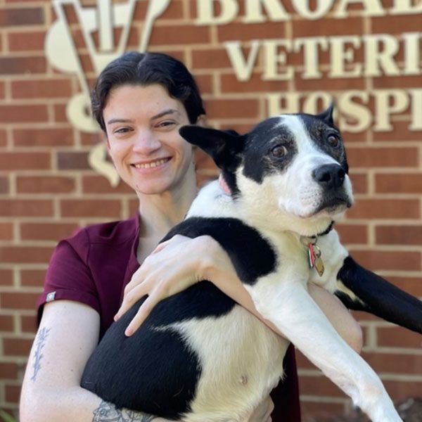 Christi posing for a picture outdoors with a black and white dog in front of a brick wall