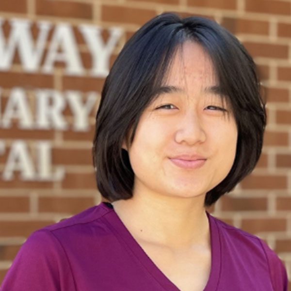 Rena posing for a picture outdoors in front of a brick wall